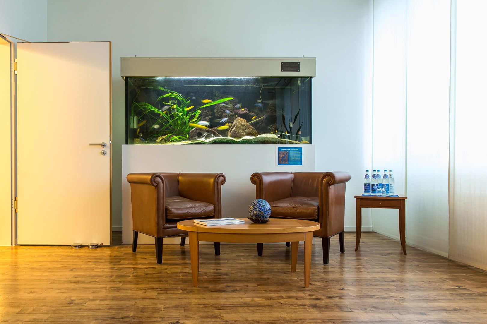 Wartebereich mit Aquarium und braunen Ledersesseln